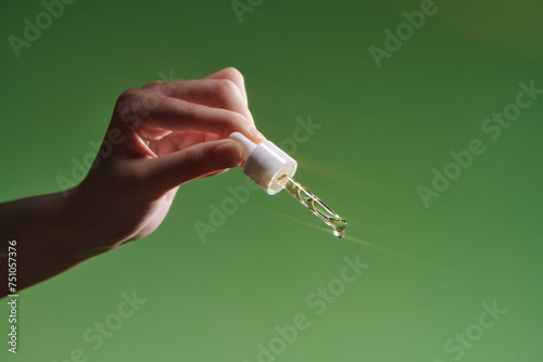 Hand of woman holding cosmetic serum pipette photo