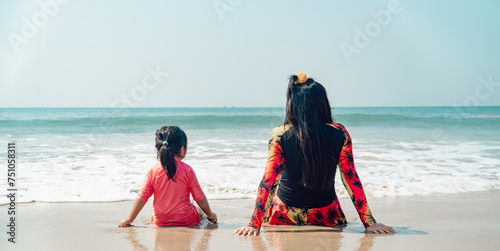 mother and little daughter sitting on sea beach. family on the beach concept.