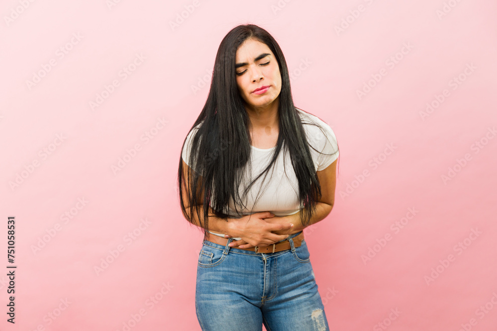Sick young woman in pain because of cramps - obrazy, fototapety, plakaty 