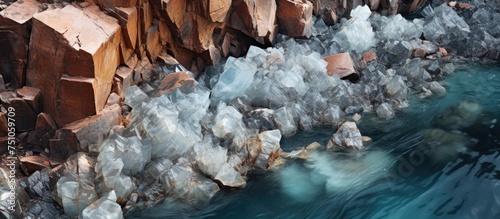 This aerial view showcases a body of water enclosed by jagged rocks. The water appears polluted, with iron sulfate crystals visible, possibly a result of nearby abandoned open pit copper mining