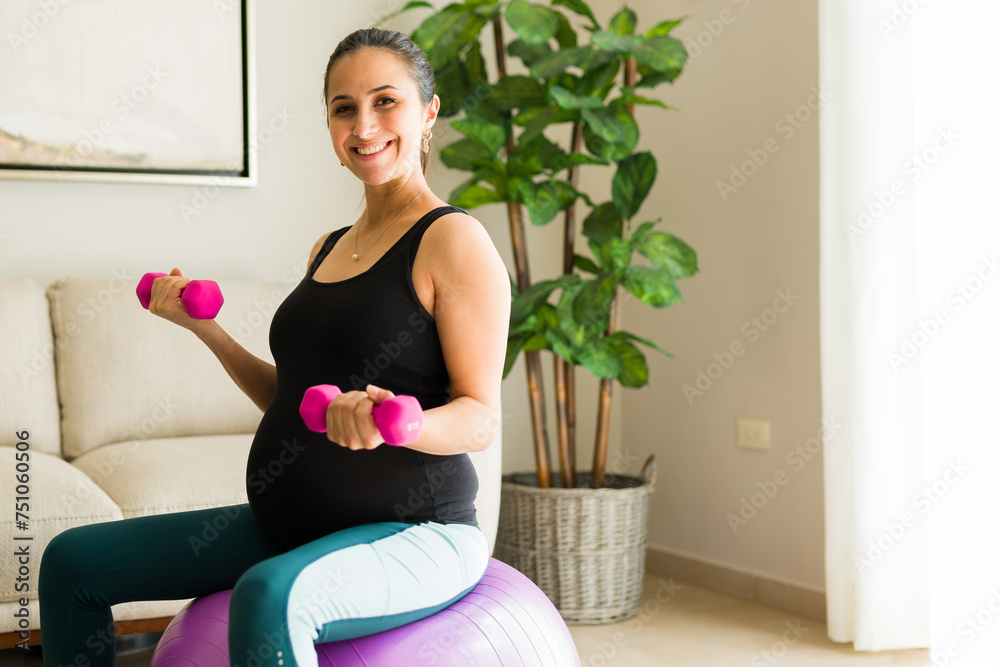 Excited pregnant woman exercising with dumbbells and a fitness ball Excited pregnant woman exercising with dumbbells and a fitness ball