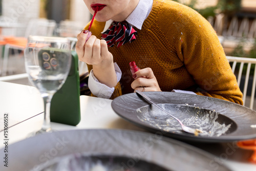 woman applying lipstick in restaurant after meal photo