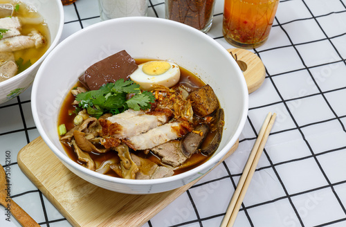 Guay Jub, Chinese roll noodle soup with boiled eggs and crispy pork in a white bowl.  it’s one of the top Thai Street Food photo