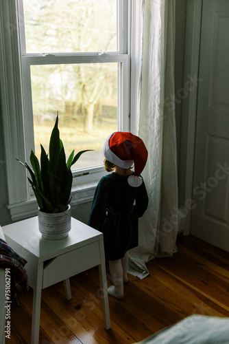 toddler standing by a window dressed like an elf photo