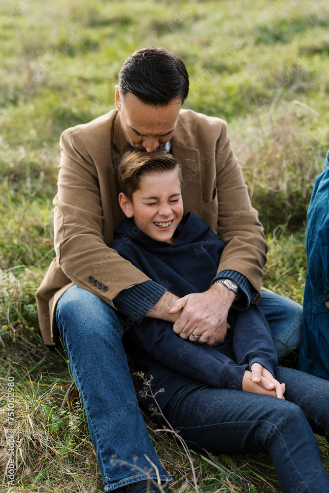 middle aged father hugging his tween son middle aged father hugging his tween son
