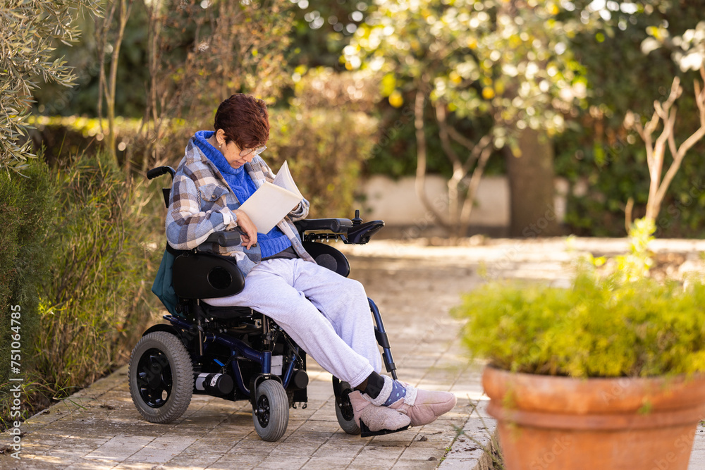 Woman with mobility difficulties reading a book at garden Woman with mobility difficulties reading a book at garden