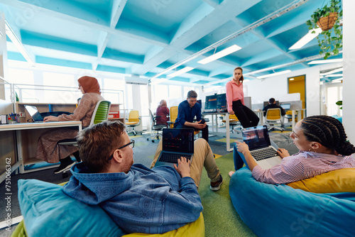 In a modern startup office, a diverse group of young and capable businesspeople engage in lively discussions about various projects, showcasing teamwork, innovation, and entrepreneurial spirit