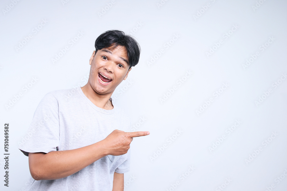 Asian man in casual clothes pointing finger to the empty space for ads or text with happy expression Asian man in casual clothes pointing finger to the empty space for ads or text with happy expression