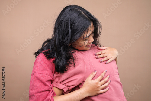 Two young Asian women embracing each other at home.