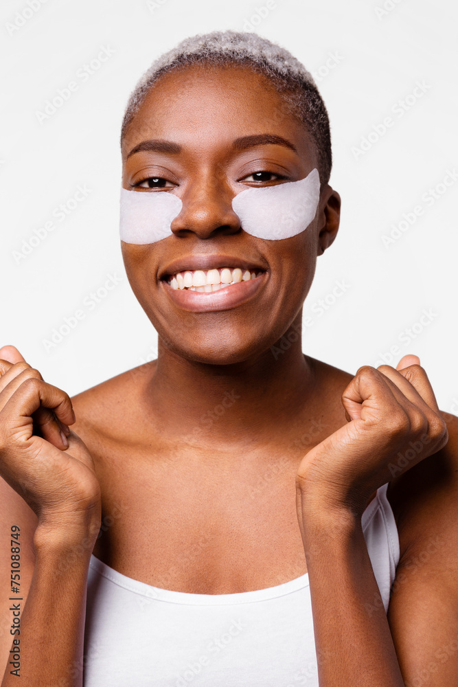 Smiling young woman with an anti-wrinkle patch under her eyes Smiling young woman with an anti-wrinkle patch under her eyes