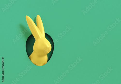 Creative composition with yellow Easter bunny rabbit peeking out from hole on green  background. Creative art, minimal aesthetic look. Contemporary style. Minimal easter concept, with writing space an