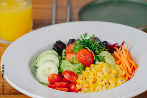 A colorful salad with a glass of orange juice on the side