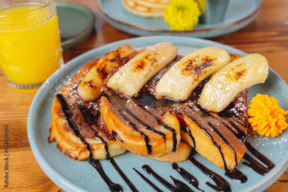A plate of banana bread with chocolate sauce and a glass of orange juice A plate of banana bread with chocolate sauce and a glass of orange juice