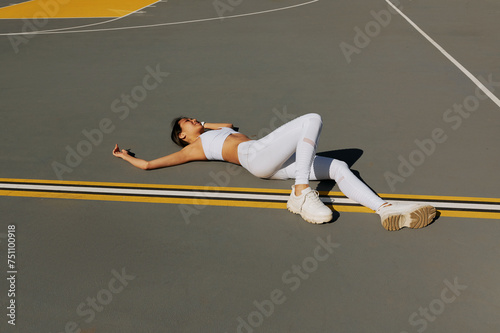 woman in leggings, sports top lies on the floor of a sports playground photo