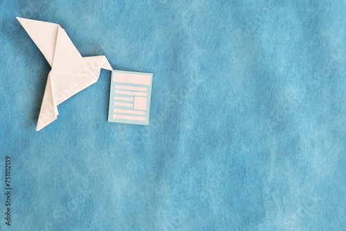 White paper dove origami carrying email newsletter document in blue background.