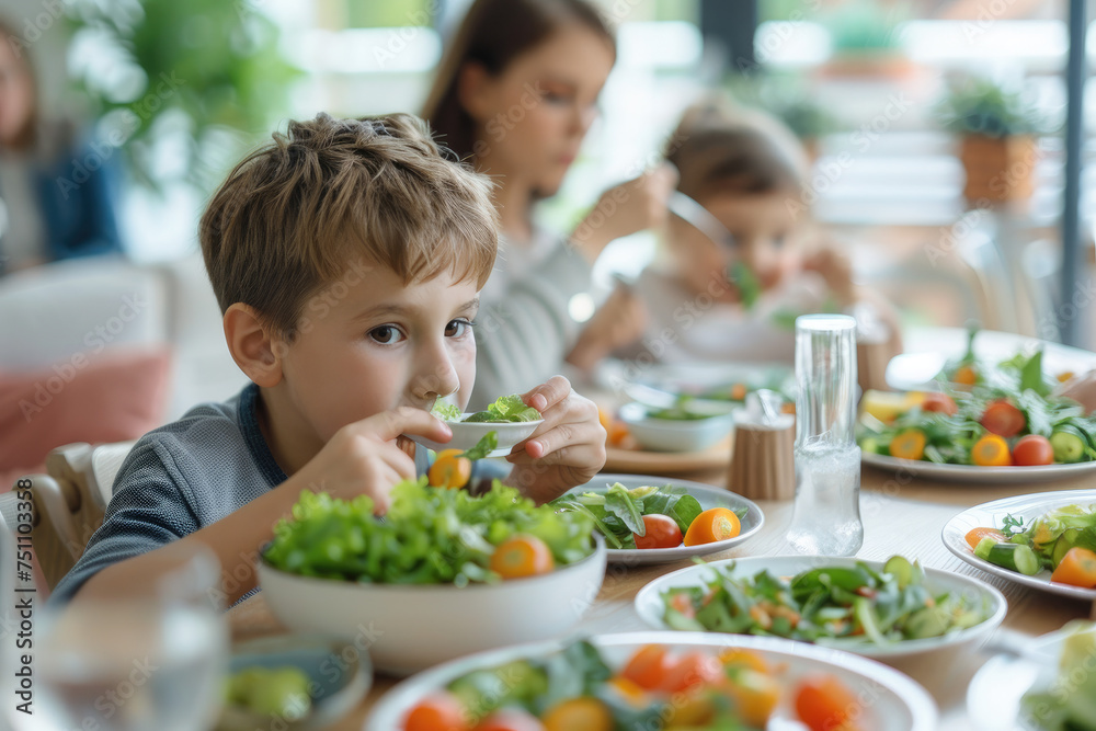 Small kid eats salad while having family lunch at dining table at home, healthy food concept