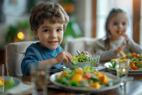 Small kid eats salad while having family lunch at dining table at home  healthy food concept