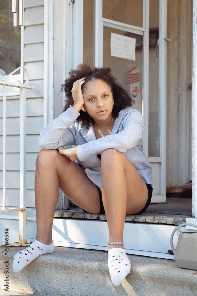 Teenager girl sitting outside on the top stairs of her home Teenager girl sitting outside on the top stairs of her home