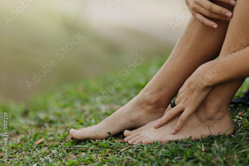 Crop barefooted female resting on grassy lawn in park photo