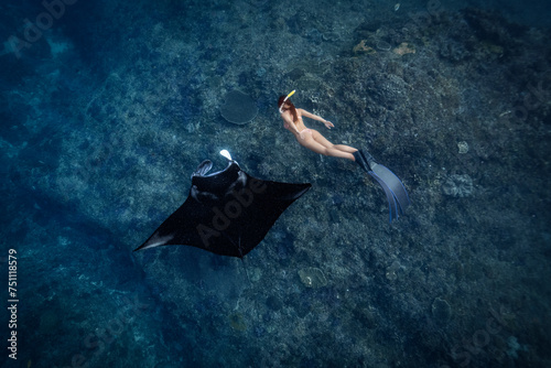 Female Freediver swimming with manta ray at the cleaning station photo