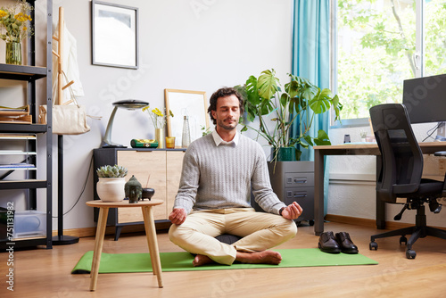 Self-employed man meditating on mat after workday photo