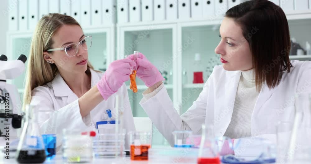 Team of chemists compares colors of two chemical liquids in test tubes in laboratory Team of chemists compares colors of two chemical liquids in test tubes in laboratory
