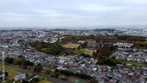 A sprawling cityscape with residential areas and green spaces on an overcast day, crane in distance, aerial view