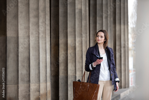 Caucasian business woman using smartphone in front of courthouse.