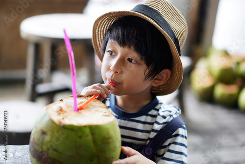 Asian little boy, drinking fresh coconut juice by the sea