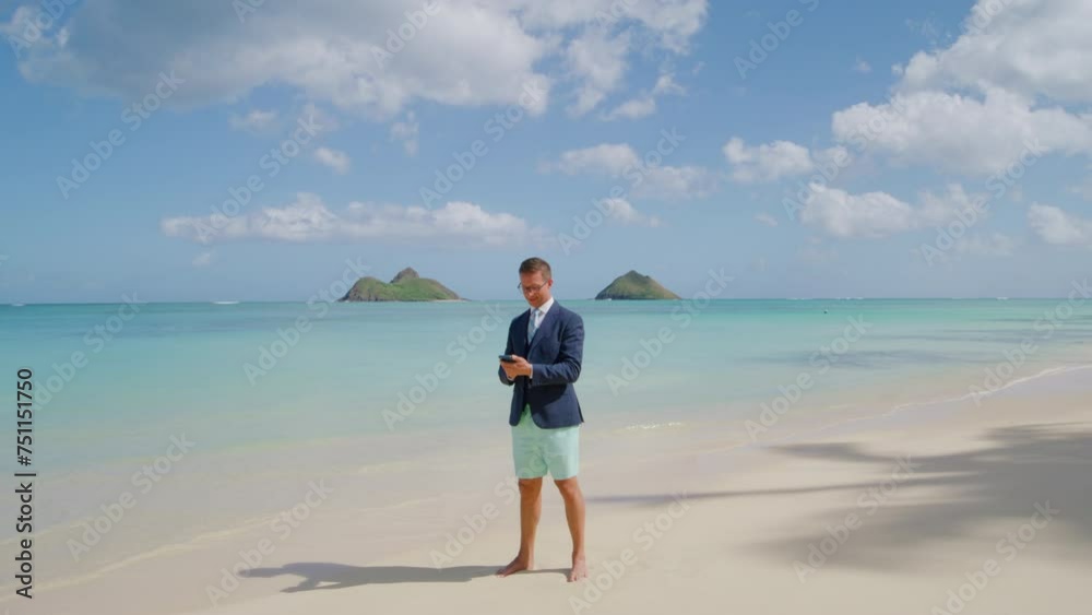 Businesslike person in jacket and beach shorts using mobile phone standing barefoot on shore washed by calm tranquil waters of the Pacific ocean, Oahu. High quality 4k footage Businesslike person in jacket and beach shorts using mobile phone standing barefoot on shore washed by calm tranquil waters of the Pacific ocean, Oahu. High quality 4k footage