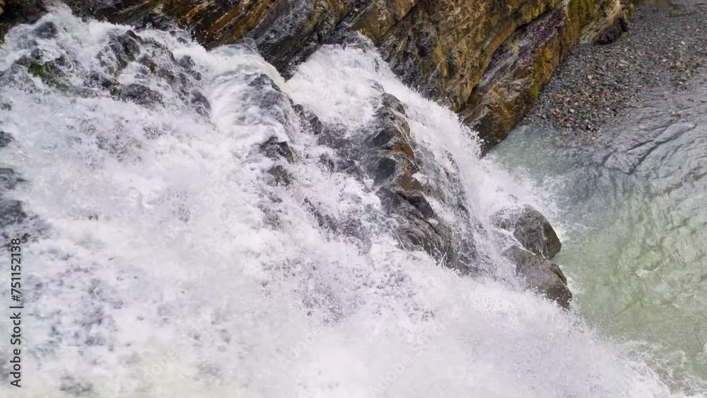 A stream of clear mountain water cascades down rocks in the mountains. Waterfall in a mountainous area. A stream of clear mountain water cascades down rocks in the mountains. Waterfall in a mountainous area.