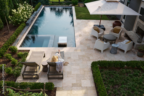 Top down view of a woman relaxing poolside with a book 