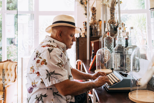 Old cuban man typing on vintage typewriter photo