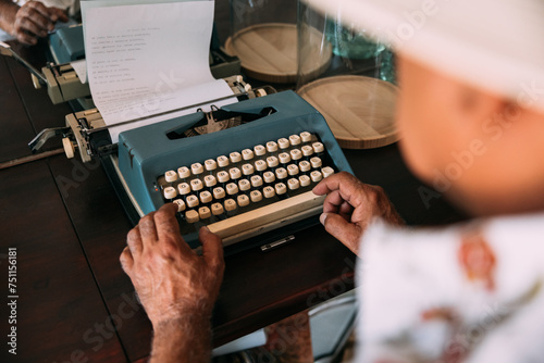 Crop man typing poem on vintage typewriter photo