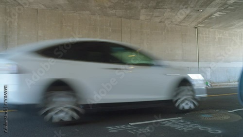 Homeless encampment under an overpass with personal belongings scattered around, daylight