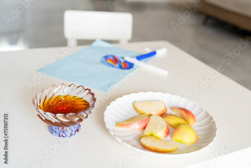 Honey and Plate of Sliced Apples on Table with Children's Drawing. photo