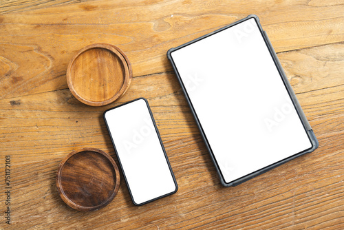 A smartphone and a tablet with blank screens lie next to two small wooden bowls on a textured table,