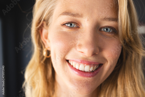 Young Caucasian woman with blonde hair and blue eyes is smiling at the camera