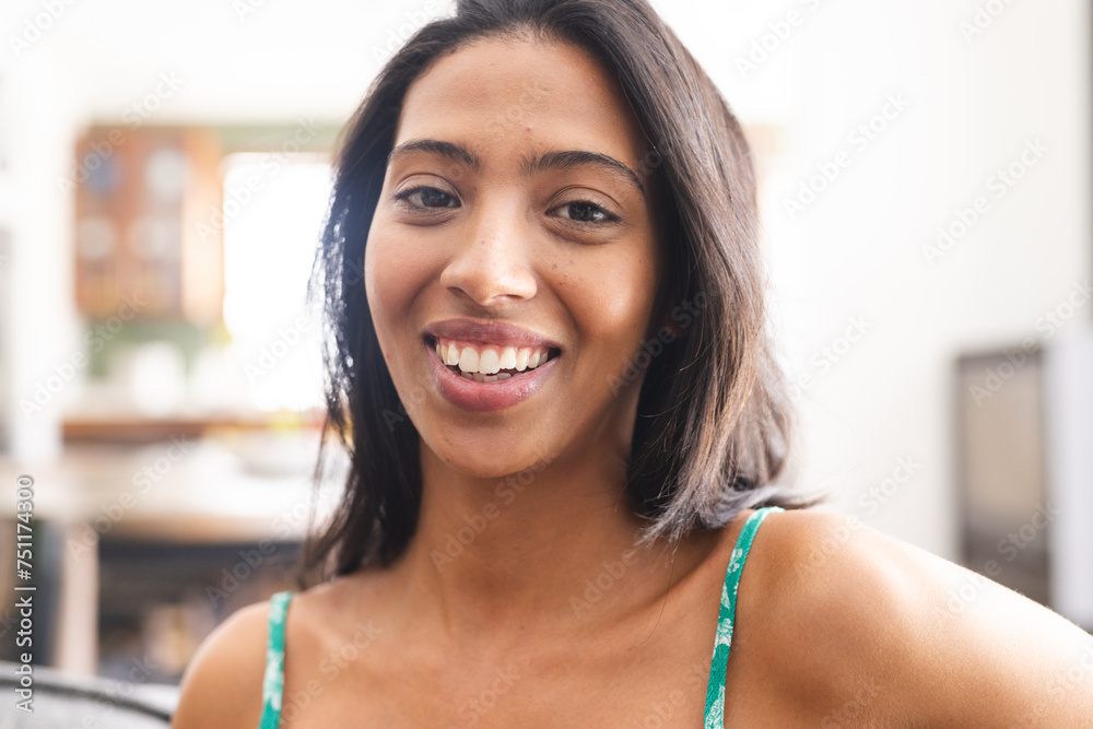 Young biracial woman with a cheerful smile, wearing a green top
