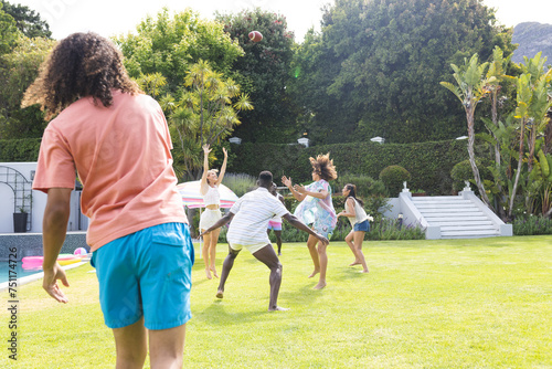 Diverse group of friends playing with a football in a sunny backyard with copy space