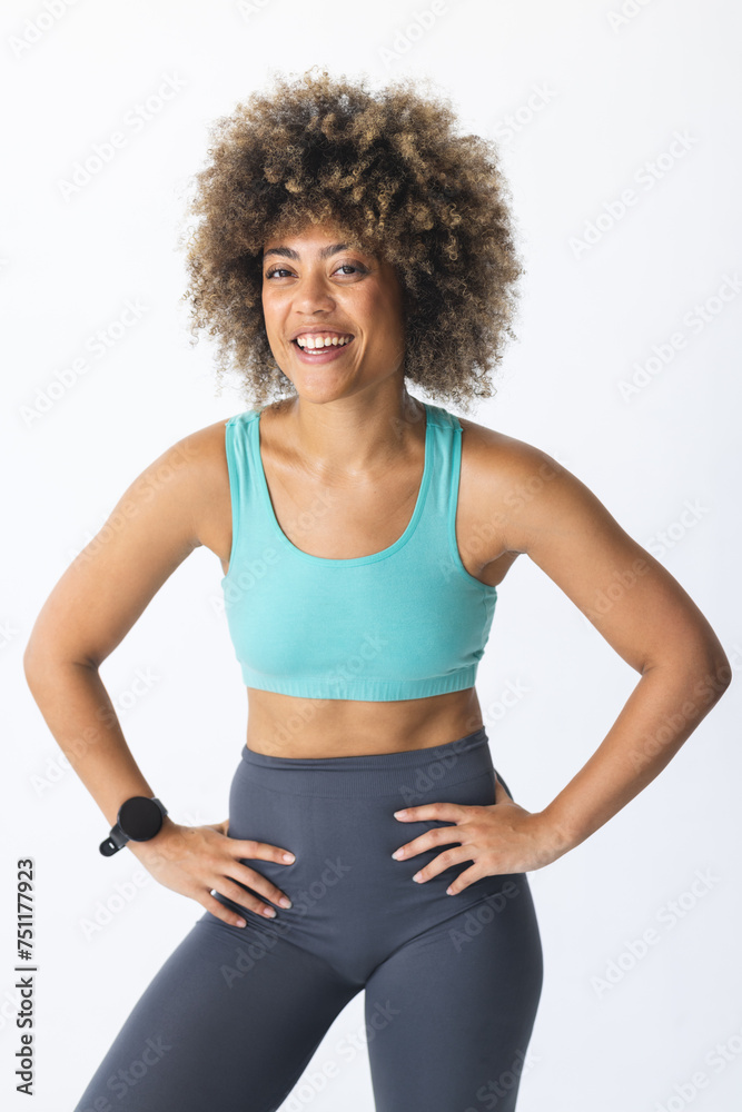 A young biracial woman poses confidently in fitness attire
