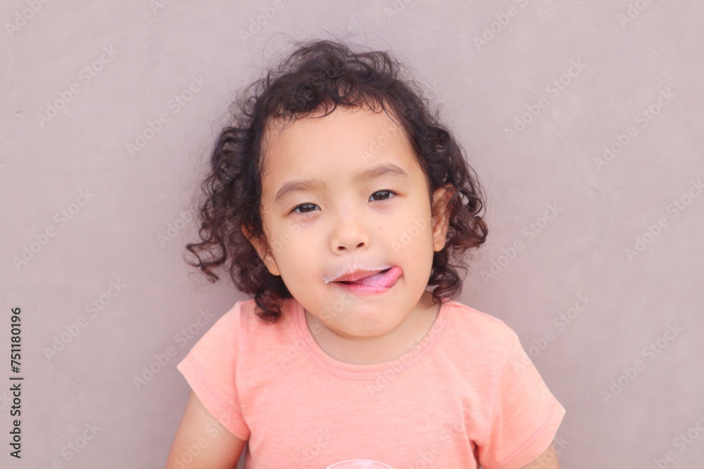 Fototapeta premium Expression of a toddler girl drinking milk in a glass.