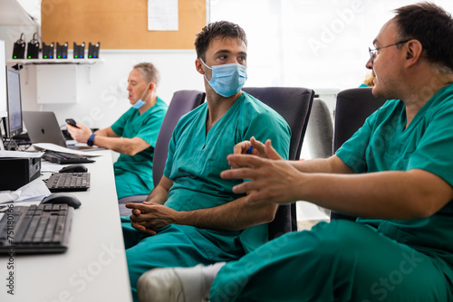 Doctors sitting and discussing at desk with gadgets photo