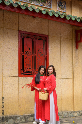 Happy Vietnamese mother and daughter in red ao dai dress in the park outdoor © Cuong