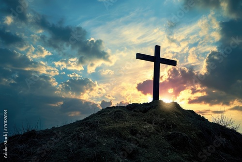Wooden cross on a hill with dramatic sunset sky. photo
