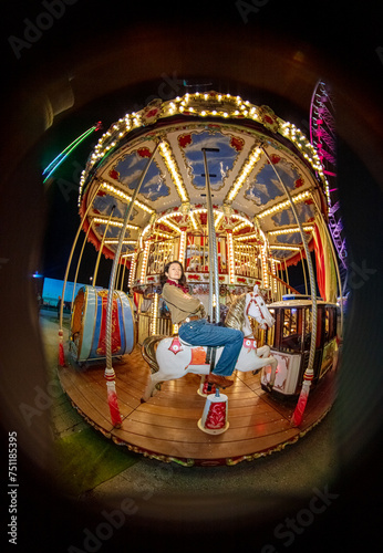 An attractive girl sits proudly on a bright children's carousel photo