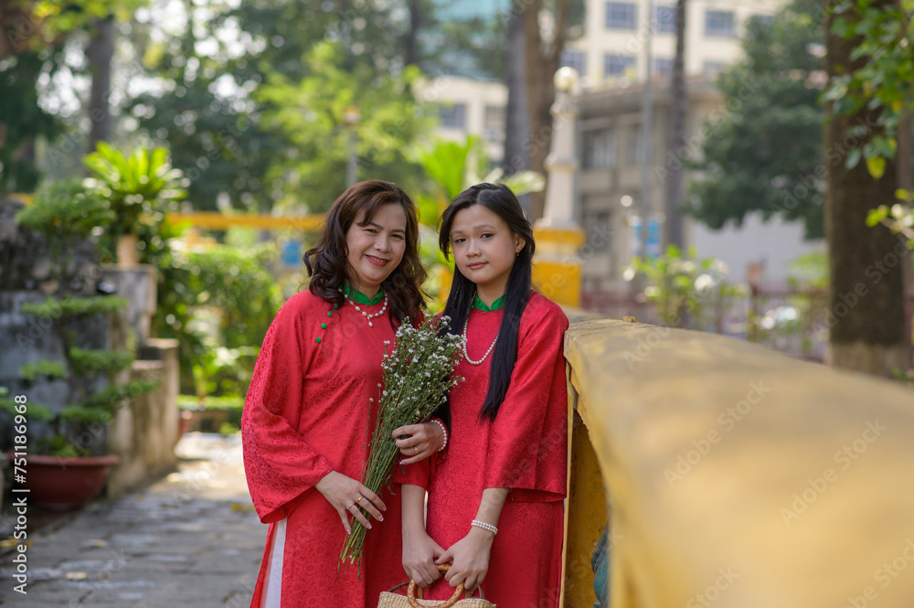 Portrait of Vietnamese mother and daughter in red Ao Dai Dress visit the pagoda on Tet holiday , Lunar new year