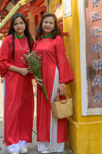Portrait of Vietnamese mother and daughter in red Ao Dai Dress visit the pagoda on Tet holiday , Lunar new year © Cuong
