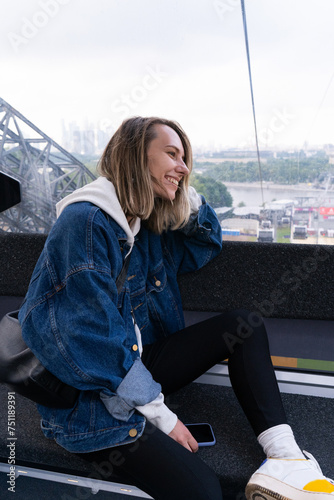 Woman looks at the city from the funicular cabin and smiles  photo