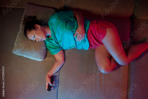 Bored woman lying on sofa doing channel surfing  photo